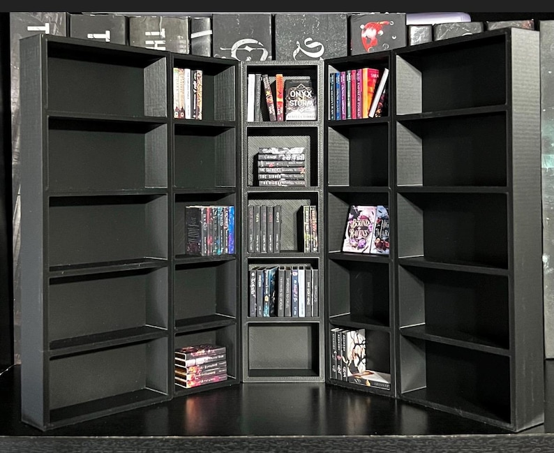 May include: A black bookshelf with five shelves on each side and three shelves in the middle. The shelves are filled with books, some of which have titles visible, such as "Onyx Stories" and "Dark Rivers".