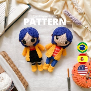 May include: Two crocheted amigurumi dolls with blue hair and yellow jackets. The dolls are wearing black and blue clothing. The dolls are sitting on a white surface with a book, a basket, and a pumpkin in the background. The text "The Looped Crafts PATTERN" is at the top of the image.