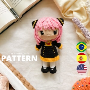 May include: Crochet amigurumi doll pattern featuring a girl with pink hair, black dress, and yellow trim. The pattern is available in English, Spanish, Portuguese, and French. The Looped Crafts logo is visible in the image.