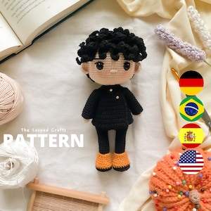 May include: Crochet amigurumi pattern for a black-haired boy doll wearing a black jacket and orange shoes. The pattern is called "The Looped Crafts" and is displayed on a white background with yarn and a wooden frame.