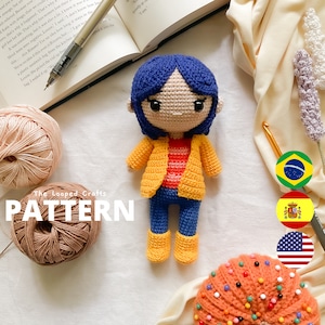 May include: Crochet amigurumi pattern for a girl doll with blue hair, wearing a yellow jacket, red and white striped shirt, blue jeans, and yellow boots. The pattern is available in English, Spanish, Portuguese, and Brazilian Portuguese. The image also includes yarn, a crochet hook, and a pincushion.