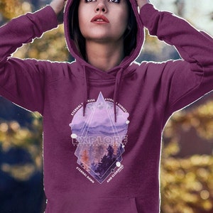 May include: A maroon hoodie with a geometric design featuring a mountain range, trees, and the word "Explore". The design is in shades of purple and pink.