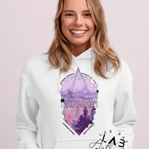 May include: White hoodie with a purple and pink geometric design featuring a mountain landscape and the text "EXPLORE THE GREAT OUTDOORS". The design also includes the text "Eternal Sunrise", "Eternal Sunset", "Eternal Dawn", and "And Gloaming".