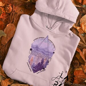May include: A lavender hoodie with a geometric design featuring a watercolor landscape and the text "Explore the Great Outdoors" with the words "Eternal Sunrise", "Eternal Sunset", "Eternal Dawn", and "And Gloaming" around the design.