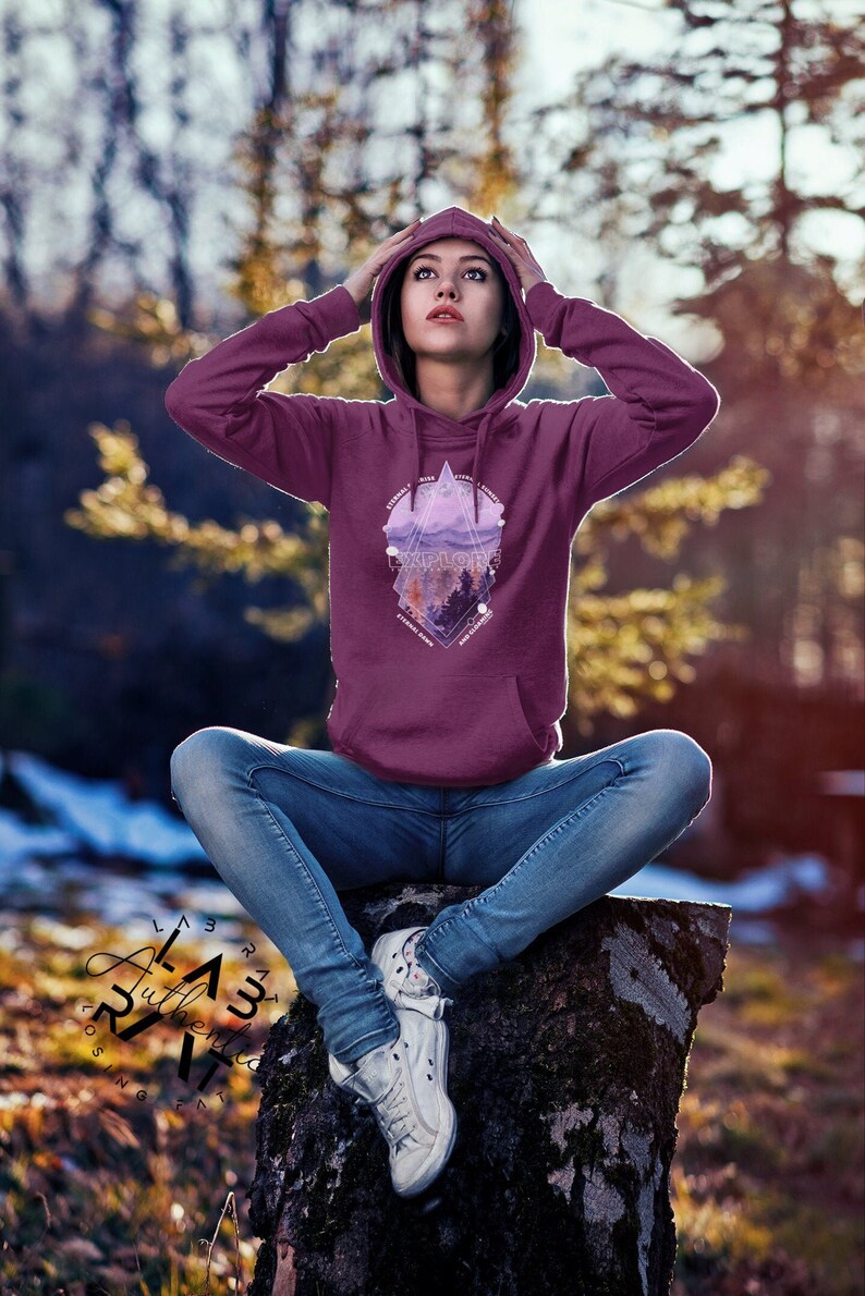 May include: A maroon hoodie with a geometric design featuring a mountain range, trees, and the word "Explore". The design is in shades of purple and pink.