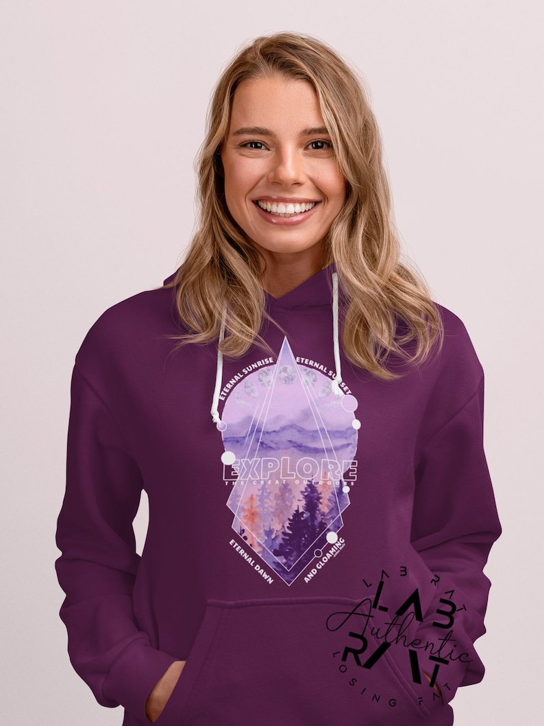 May include: Purple hoodie with a geometric design featuring a watercolor landscape with trees and the text "EXPLORE THE GREAT OUTDOORS" in white. The design also includes the text "ETERNAL SUNRISE", "ETERNAL SUNSET", "ETERNAL DAWN", and "AND GLOAMING". The hoodie has a white drawstring and a kangaroo pocket.