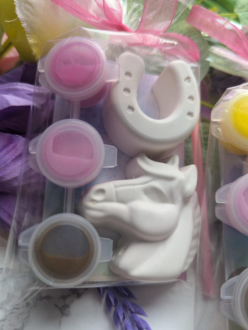 Puede incluir: Un kit de manualidades en una bolsa de pl&aacute;stico transparente que contiene una herradura de yeso blanco y una figura de cabeza de caballo de yeso blanco. El kit incluye tres peque&ntilde;os botes de pintura redondos con pintura rosa y marr&oacute;n.