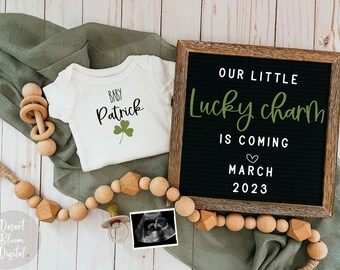 May include: A baby announcement with a white onesie that says "Baby Patrick" with a green shamrock. A black letter board reads "Our Little Lucky Charm Is Coming March 2023." A wooden bead garland and ultrasound image complete the announcement.
