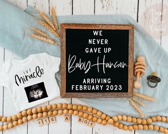 May include: A pregnancy announcement with a white onesie that says "IVF Miracle" with an ultrasound image. A black letter board reads "We Never Gave Up Baby Hansen Arriving February 2023". Wooden beads and a baby rattle are also present.