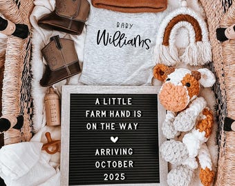 May include: A white onesie with the text "Baby Williams" on it, a brown beanie, a pair of brown cowboy boots, a crocheted cow toy, a wooden letter block spelling "BABY", a wooden rattle, a brown and white crocheted rainbow, a letter board with the text "A little farm hand is on the way arriving October 2025", and a wooden bottle.