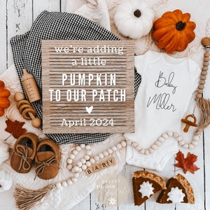 May include: A white onesie with the text "Baby Miller" in black script. The onesie is surrounded by fall-themed decorations, including pumpkins, leaves, and a letter board that reads "we're adding a little PUMPKIN TO OUR PATCH April 2024".