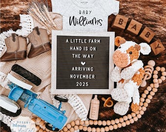 May include: A letter board with the text "A little farm hand is on the way arriving November 2025". A baby onesie with the text "Baby Williams" is in the background. There are also wooden blocks that spell out "BABY" and a crocheted cow toy.
