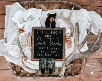 May include: A black letter board with the text "Rifles, Racks and Deer Tracks That's What Little Boys Are Made Of" surrounded by antlers, a baby onesie, a stuffed bear, and other baby items.