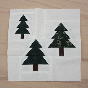 Könnte beinhalten: Drei Stoff-Weihnachtsbäume auf weißem Hintergrund. Die Bäume sind unterschiedlich groß und haben unterschiedliche Muster. Der größte Baum hat ein grünes und goldenes Muster, der mittlere Baum ist einfarbig grün und der kleinste Baum ist einfarbig grün.