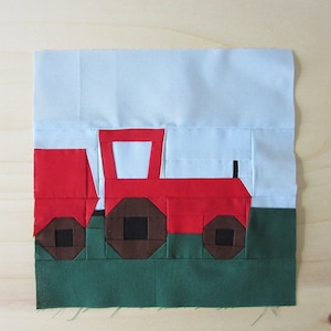 Könnte beinhalten: Ein roter Traktor mit braunen Rädern fährt über ein grünes Feld. Der Traktor hat eine weiße Kabine und einen schwarzen Auspuff. Der Hintergrund ist ein hellblauer Himmel.