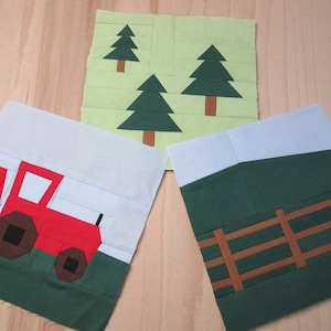 Puede incluir: Tres cuadrados de tela con diseños de patchwork. Uno presenta un tractor rojo, otro tiene árboles verdes y el tercero representa un campo verde con una valla marrón. Los cuadrados están sobre un fondo de madera clara.
