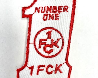 Könnte beinhalten: Roter gestickter Aufnäher mit weißem Hintergrund. Der Aufnäher ist in Form der Zahl Eins und hat den Text "NUMBER ONE" oben. Die Zahl Eins ist auch in Rot in einem Kreis gestickt, mit den Buchstaben "1 FCK" im Kreis. Der Text "1 FCK" ist auch in Rot unten auf dem Aufnäher gestickt.