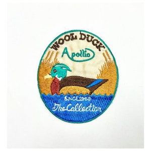 Może przedstawiać: Winietkowy, haftowany znaczek z kreskówkowym kaczorem drewno z tekstem "Wool Duck Apollo The Collection Since 1969" w kółku.