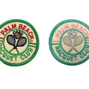 May include: Two embroidered patches with a green border and a white background. The patches feature the text "Palm Beach Racquet Club" and a tennis racket and ball design. One patch has a red and white ball, and the other has a pink and white ball.