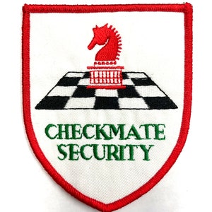 Peut inclure: Un écusson brodé blanc avec une pièce de chevalier d'échecs rouge sur un échiquier noir et blanc. Le texte "CHECKMATE SECURITY" est brodé en vert sous la pièce d'échecs.