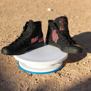 May include: A pair of black high-top trainers with a red and white graphic of a hand with claws and the text "Friday the 13th".