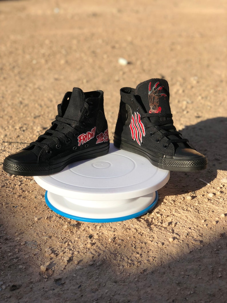 May include: A pair of black high-top trainers with a red and white graphic of a hand with claws and the text "Friday the 13th".