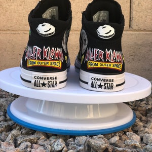 May include: A pair of black high-top Converse sneakers with custom painted designs. The sneakers feature a graphic of a clown with the text "Killer Klowns from Outer Space".