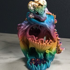 May include: A rainbow-colored 3D printed dice tower shaped like a dragon with a dragon head on top. The tower is filled with colorful dice.