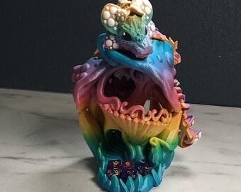 May include: A rainbow-colored 3D printed dice tower shaped like a dragon with a dragon head on top. The tower is filled with colorful dice.