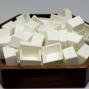 May include: A wooden tray filled with white ceramic paint pans. The pans are arranged in a random pattern and are all the same size.