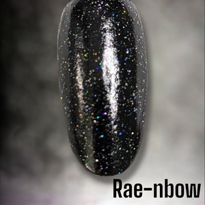 May include: A black nail polish with iridescent glitter, called "Rae-nbow Eclipse" by Bloom Dip.