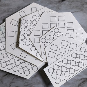 May include: A set of six white hexagon-shaped paper templates with different designs. The designs include circles, squares, and a combination of both. The templates are perfect for crafting, drawing, or creating patterns.