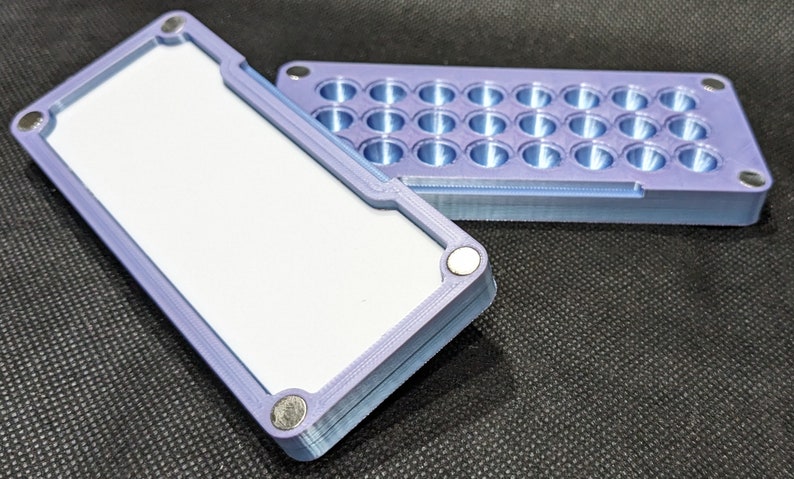 May include: A purple 3D printed box with a lid. The lid has 24 round holes. The box is made of plastic and has a smooth finish.