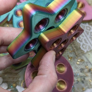 May include: A set of three iridescent fidget toys in the shape of a star, butterfly, and circle. The toys are made of a smooth, colourful plastic and have a variety of textures.