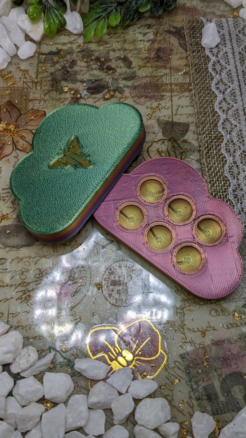 May include: Two cloud-shaped resin trays. One is green with a butterfly design and the other is pink with six circular indentations.