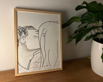 May include: A black and white line drawing of a couple embracing, framed in a light wood frame.