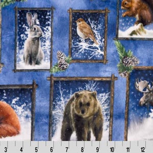 May include: A blue fabric with a repeating pattern of framed images of woodland animals. The animals include a deer, a rabbit, a bird, a fox, a bear, and a moose. The frames are made of brown wood and have a rustic look. The fabric is perfect for quilting, crafts, and home decor.