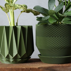 May include: Two green ceramic planters with different geometric patterns. The planter on the left has a geometric pattern with sharp angles. The planter on the right has a chevron pattern.