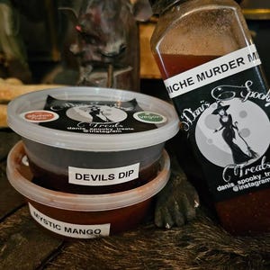 May include: Two small containers of red sauce with labels that read "Mystic Mango" and "Devils Dip". A larger bottle of red liquid with a black label that reads "MICHE MURDER MIX" and "Danis Spooky Treats".
