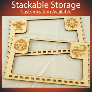 May include: Stackable wooden storage boxes with laser-cut designs. The boxes feature a skull, a symbol with a triangle and two hammers, and a logo with the text "Gamer Girl Games".