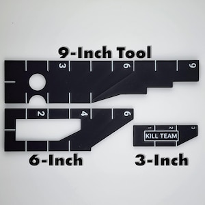 Op de afbeelding: Zwarte multi-toolset met witte markeringen en de tekst "9-Inch Tool", "6-Inch" en "3-Inch". De set bevat een tool van 22,86 cm, een tool van 15,24 cm en een tool van 7,62 cm met de tekst "KILL TEAM".