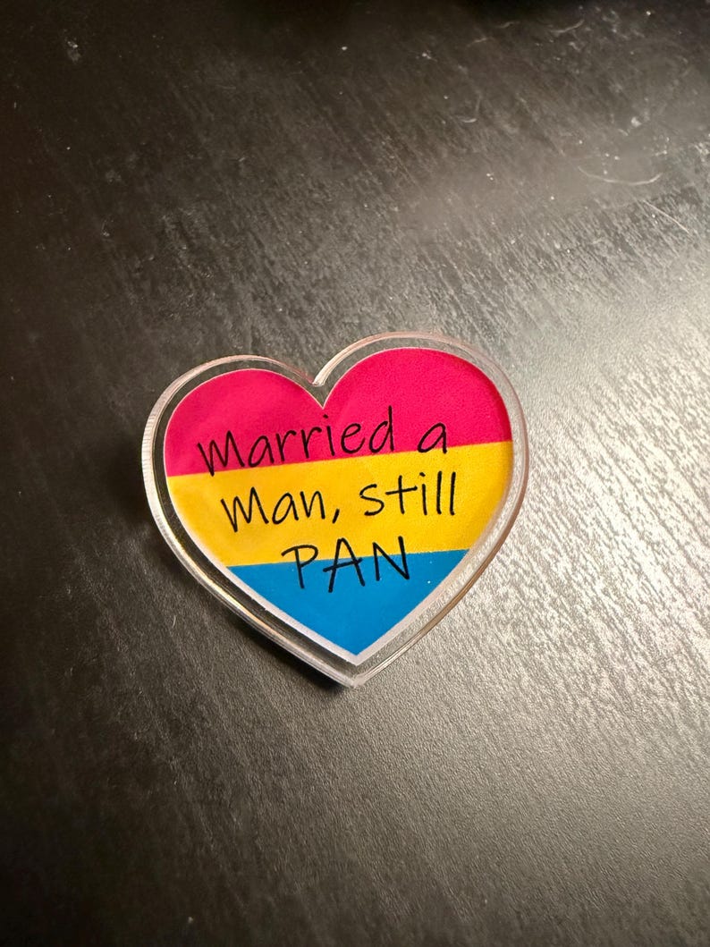 Quality acrylic pin badge in a Heart shape. This acrylic pin features a Pansexual flag. The text Reads: "Married a man still pan". Pan erasure is real. This may help in those situations where you’re asked “Why are you here then.” IYKYK