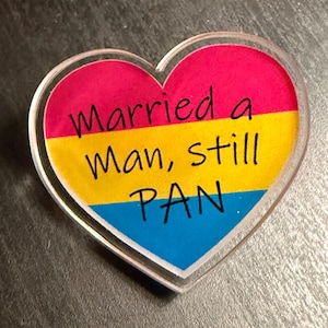 Quality acrylic pin badge in a Heart shape. This acrylic pin features a Pansexual flag. The text Reads: "Married a man still pan". Pan erasure is real. This may help in those situations where you’re asked “Why are you here then.” IYKYK