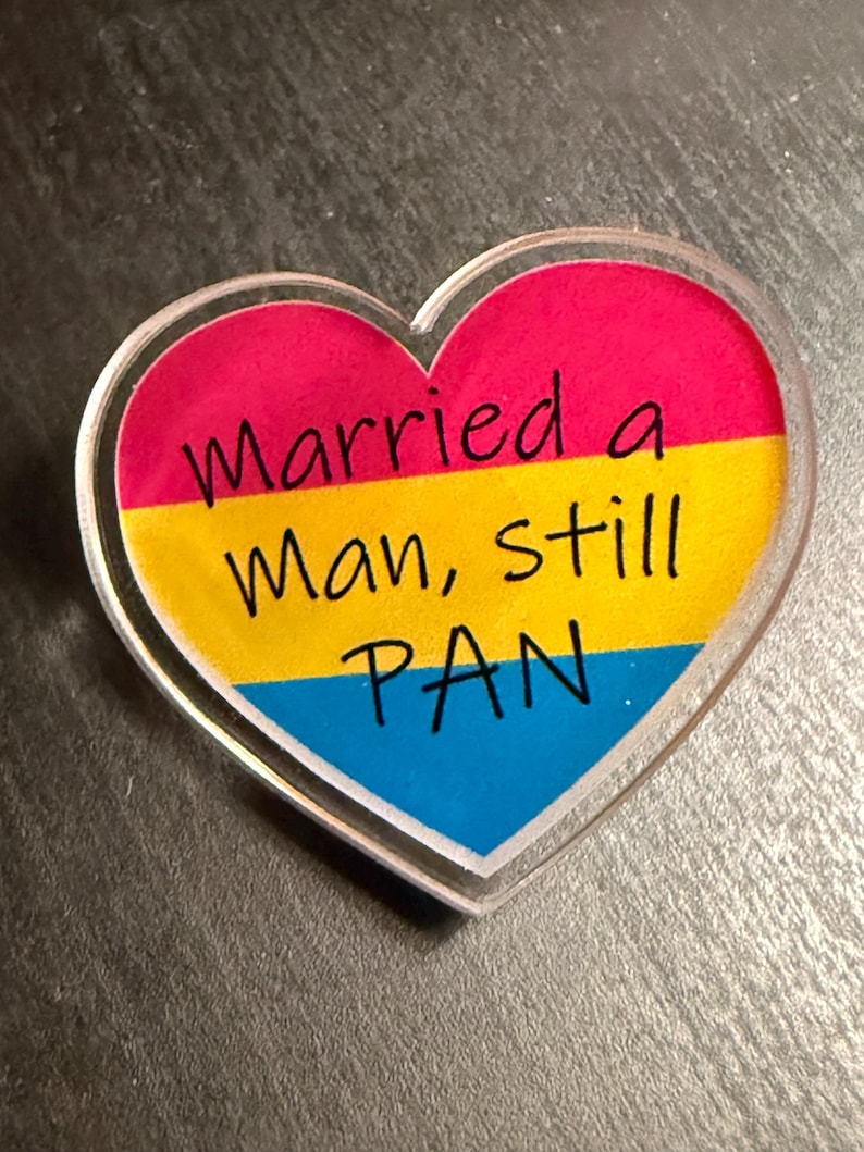 Quality acrylic pin badge in a Heart shape. This acrylic pin features a Pansexual flag. The text Reads: "Married a man still pan". Pan erasure is real. This may help in those situations where you’re asked “Why are you here then.” IYKYK