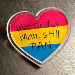 Quality acrylic pin badge in a Heart shape. This acrylic pin features a Pansexual flag. The text Reads: "Married a man still pan". Pan erasure is real. This may help in those situations where you’re asked “Why are you here then.” IYKYK