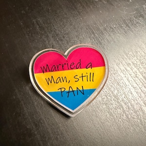 Quality acrylic pin badge in a Heart shape. This acrylic pin features a Pansexual flag. The text Reads: "Married a man still pan". Pan erasure is real. This may help in those situations where you’re asked “Why are you here then.” IYKYK