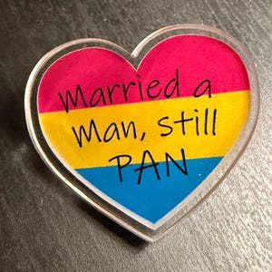 Quality acrylic pin badge in a Heart shape. This acrylic pin features a Pansexual flag. The text Reads: "Married a man still pan". Pan erasure is real. This may help in those situations where you’re asked “Why are you here then.” IYKYK