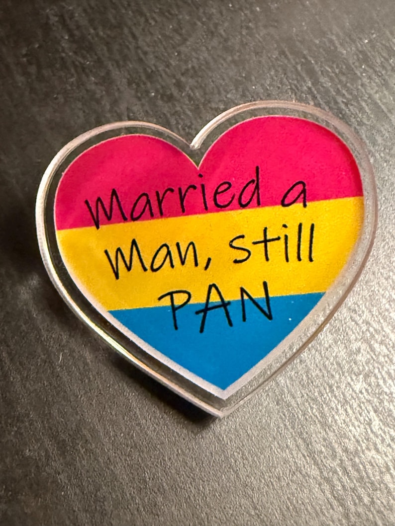 Quality acrylic pin badge in a Heart shape. This acrylic pin features a Pansexual flag. The text Reads: "Married a man still pan". Pan erasure is real. This may help in those situations where you’re asked “Why are you here then.” IYKYK