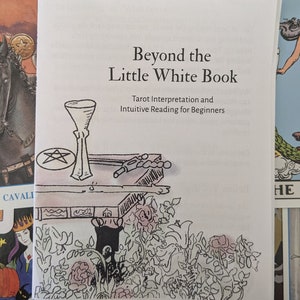 May include: A white book with the title "Beyond the Little White Book: Tarot Interpretation and Intuitive Reading for Beginners". The cover features a black and white illustration of a table with a chalice, a pentagram, and a book.