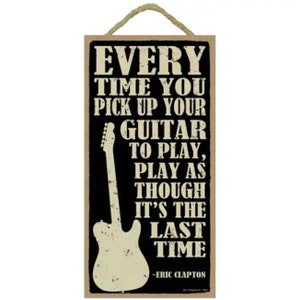 May include: A black and white wooden sign with a quote from Eric Clapton about playing guitar. The quote reads "Every time you pick up your guitar to play, play as though it's the last time."